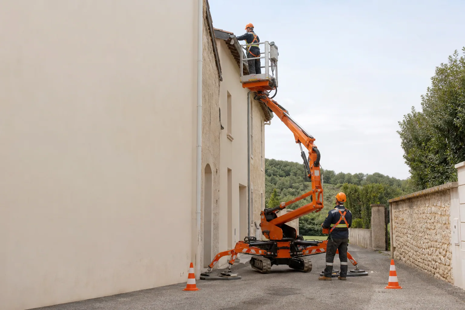 Une nacelle élévatrice orange intervient sur un bâtiment avec un technicien dans le panier et un opérateur au sol, dans le secteur de Agen.