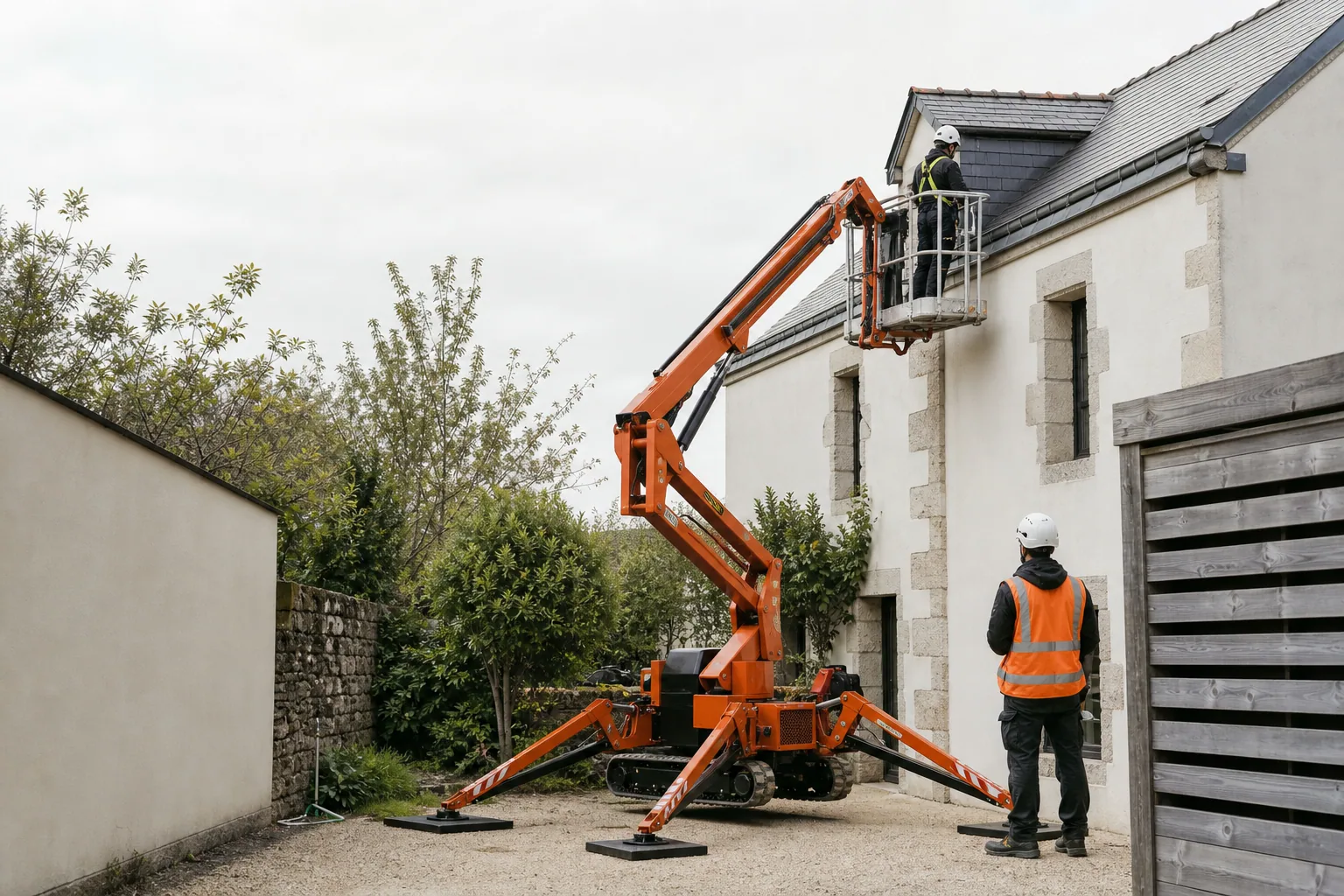 Une nacelle élévatrice orange intervient sur un bâtiment avec un technicien dans le panier et un opérateur au sol, dans le secteur de Vannes.